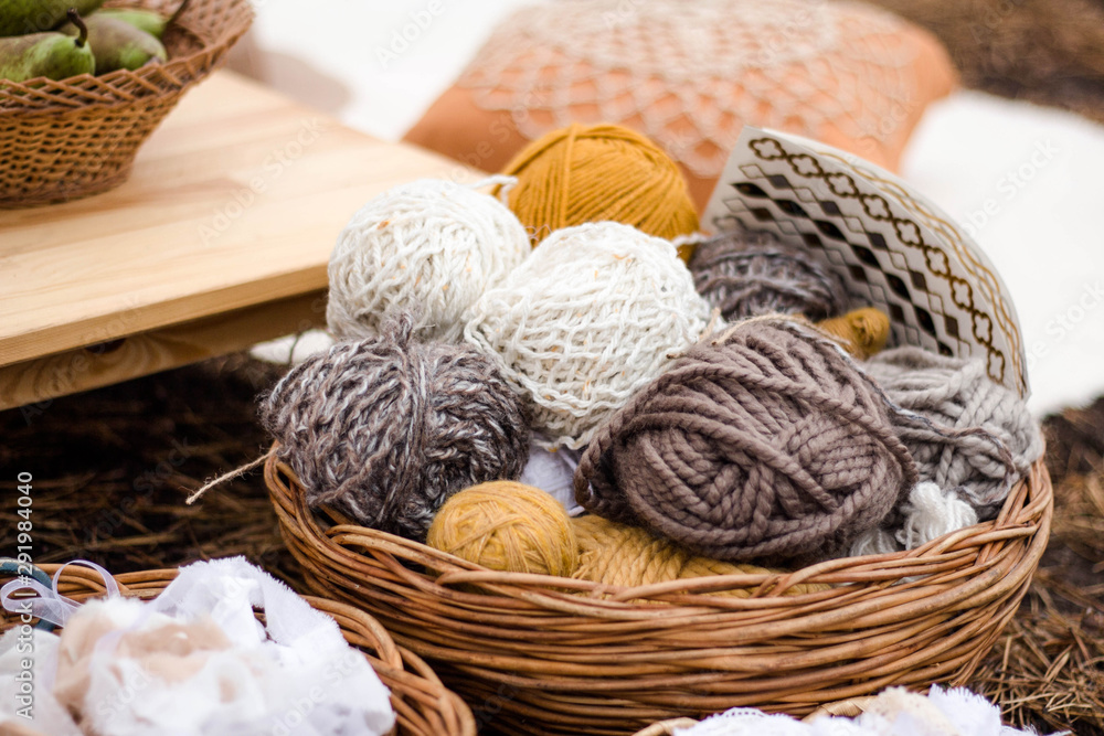 Skeins of white, gray, yellow color in a basket on a table background. close-up. Sewing tools