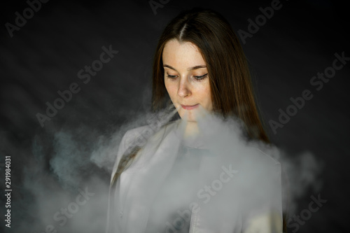 Vape teenager. Young cute girl in casual clothes smokes an electronic cigarette outdoors in summer day. Bad habit that is harmful to health. Vaping activity.