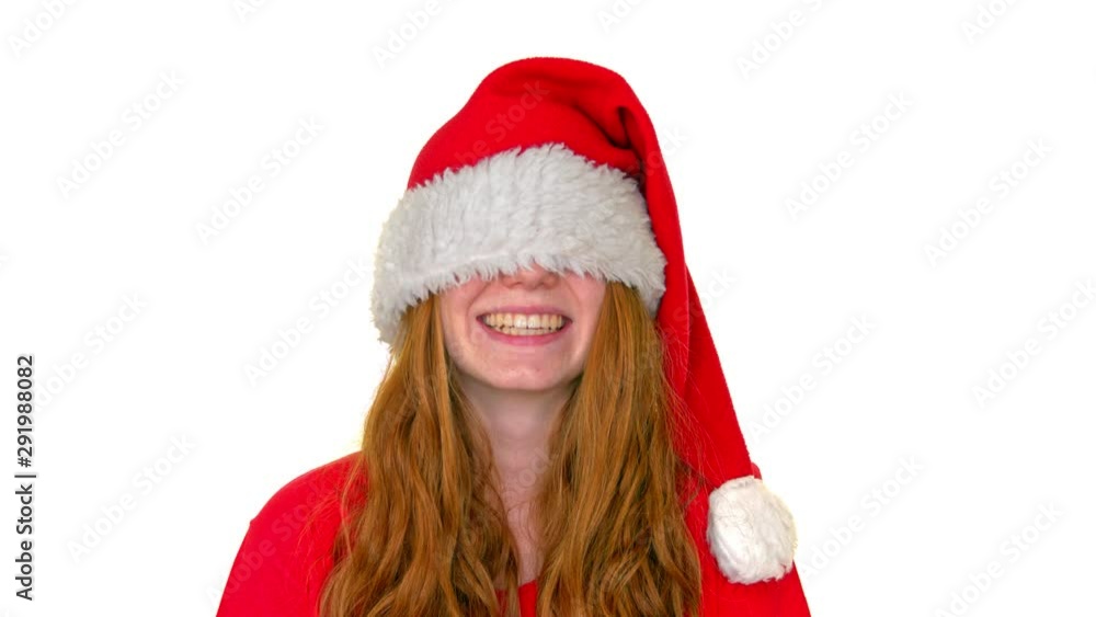 Smilling red-haired woman is wearing a christmas hat and pulled them under her eyes. Smilling red-haired woman is wearing a christmas hat and pulled them under her eyes.