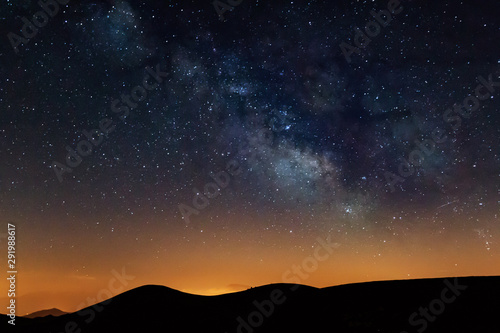 Photograph of the night sky in the mountains, with a view of the Milky Way. Visible stars during sunset. Galaxy, universe.