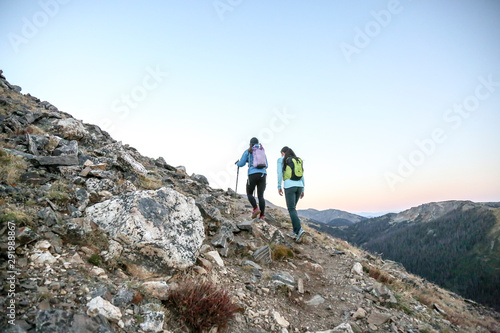 Two women trail runners push uphill in a Rocky Mountain early morning