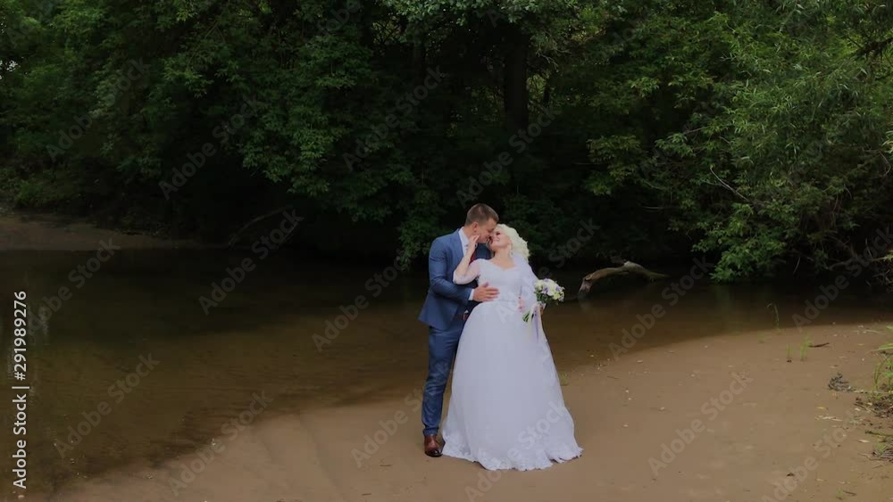 Beautiful groom and blonde bride by the creek in the forest. Beautiful groom and blonde bride by the creek in the forest.