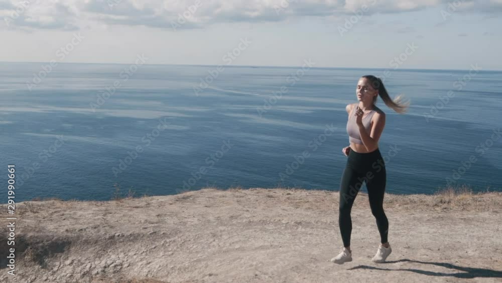 Backside view of woman running outdoors, beautiful view on ocean, slow motion Backside view of woman running outdoors, beautiful view on ocean, slow motion