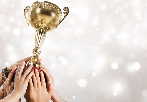 Hand holding golden trophy on blurred background