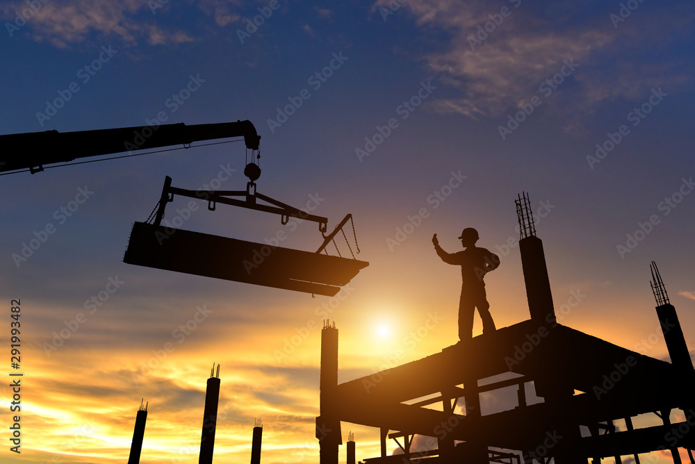 Workers in safety equipment installed concrete panels in the construction site at sunset. - obrazy, fototapety, plakaty 