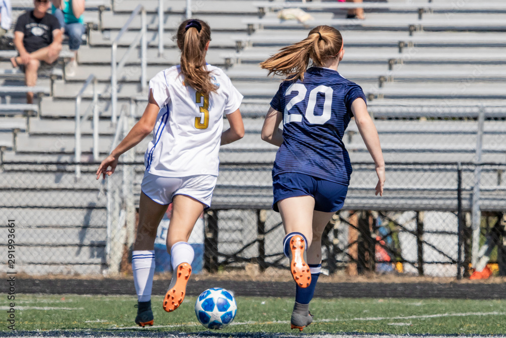 Fototapeta premium Two girls chasing soccer ball