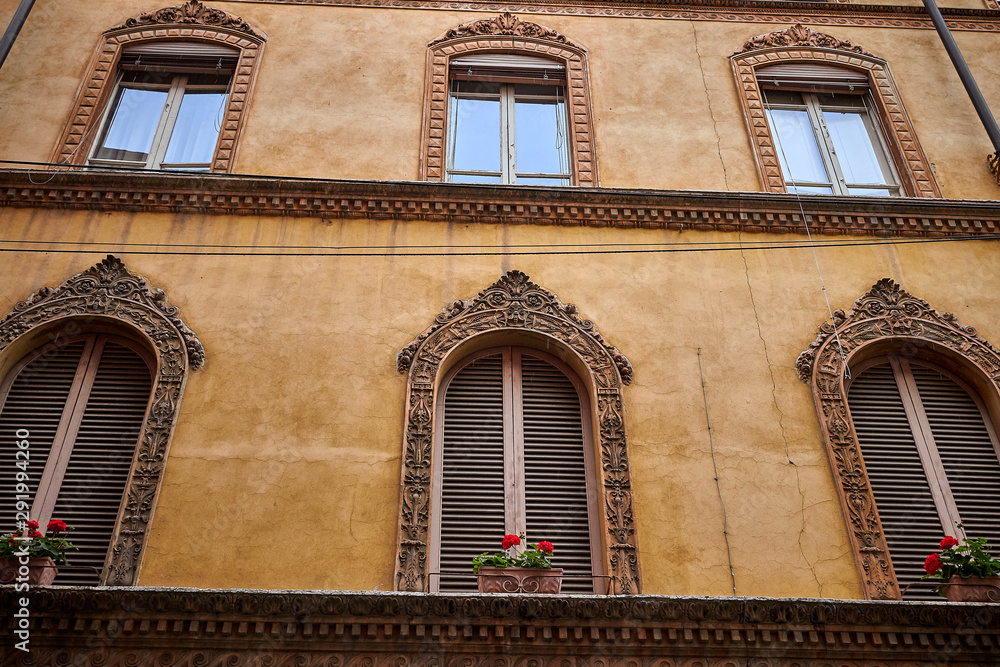 Detail of the windows and orangish wall of an antique building in Bologna, Italy.