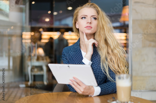 Young businesswoman on a coffee break. Using tablet computer.