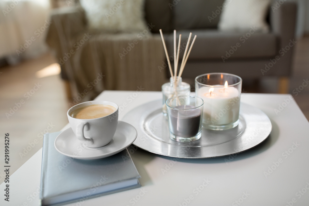 hygge and aromatherapy concept - coffee, candles, book and aroma reed diffuser on table at home - obrazy, fototapety, plakaty 