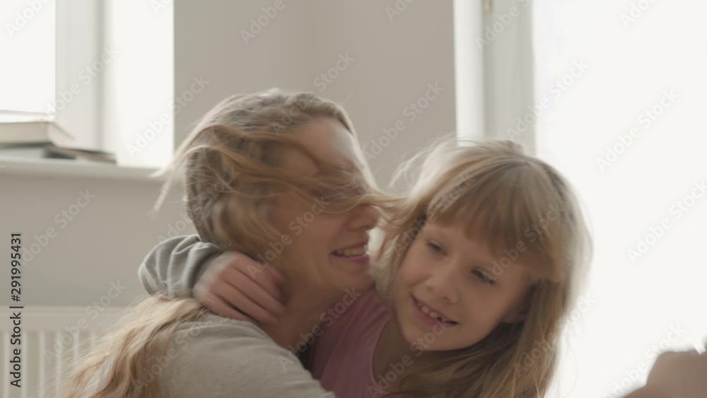 Little child's hands closing eyes of an attractive young woman. Caucasian mother with long curly hair kissing her daughter on the cheek. Little child's hands closing eyes of an attractive young woman. Caucasian mother with long curly hair kissing her daughter on the cheek.