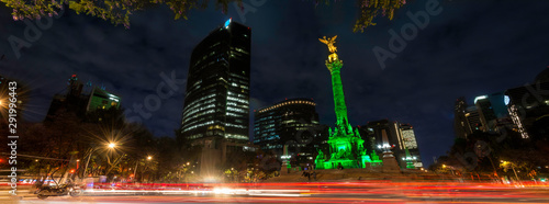 Panoramica de larga exposicion en el  Angel de la Independencia de la Ciudad de Mexico, de noche y con edificios de fondo.