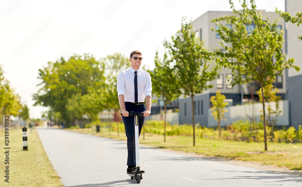 business and people and concept - young businessman riding electric scooter in city