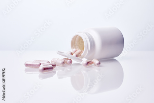Medicine, pharmacy or dietary supplement concept. Bottle with pills in capsules over white background