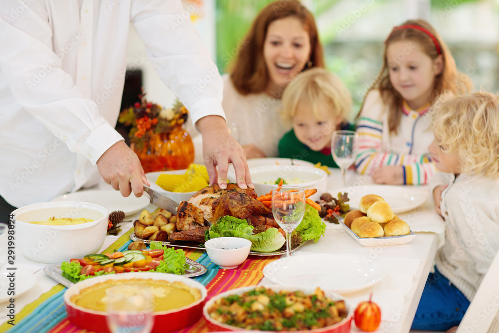 Family with kids at Thanksgiving dinner. Turkey.