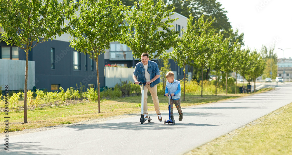 family, leisure and fatherhood concept - happy father and little son riding scooters together in city family, leisure and fatherhood concept - happy father and little son riding scooters together in city