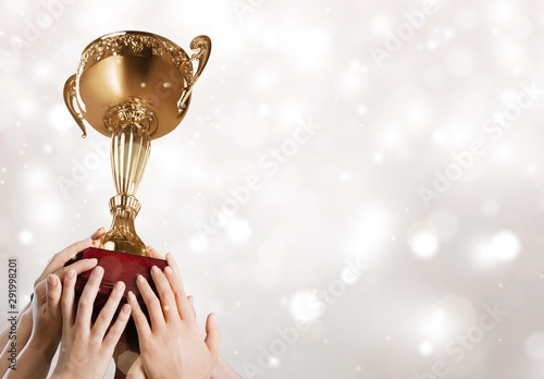 Hand holding golden trophy on blurred background