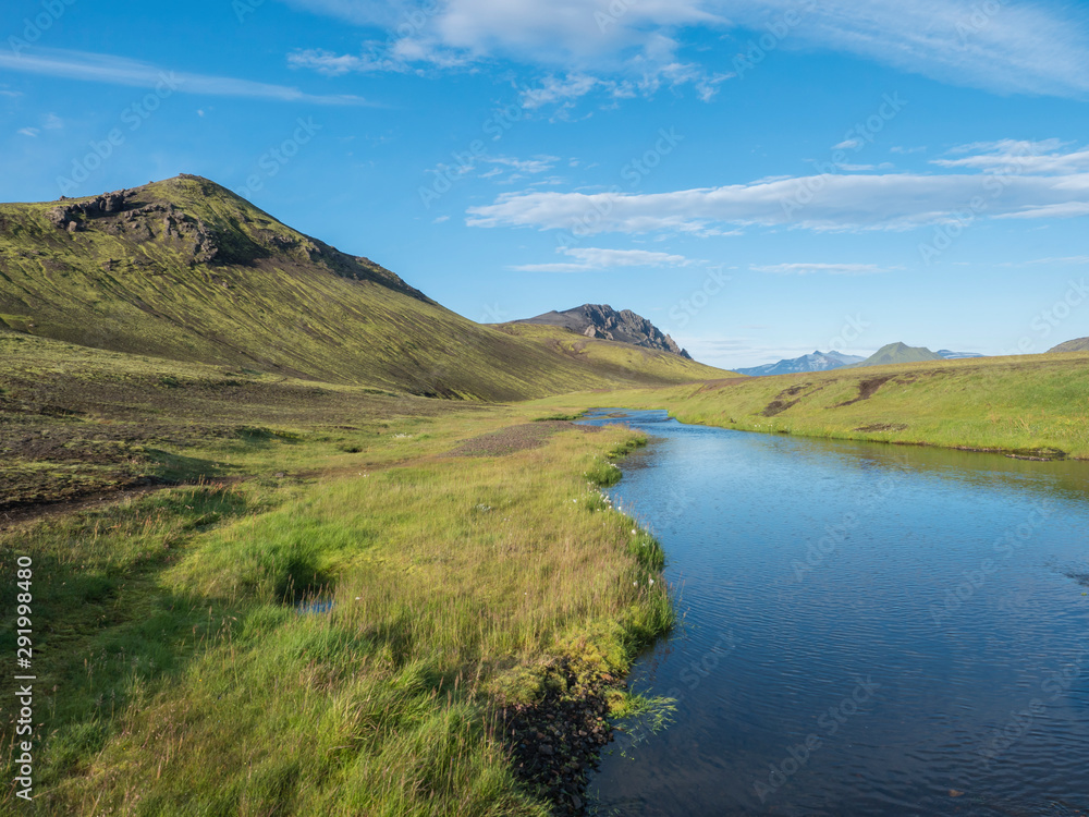 Beautiful green hills, lush grass and blue river next to camping site on Alftavatn lake. Summer sunny day, landscape of the Fjallabak Nature Reserve in Highlands Iceland part of Laugavegur hiking
