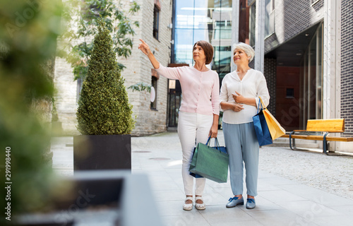 sale, consumerism and people concept - two senior women or friends with shopping bags on city street in tallinn photo