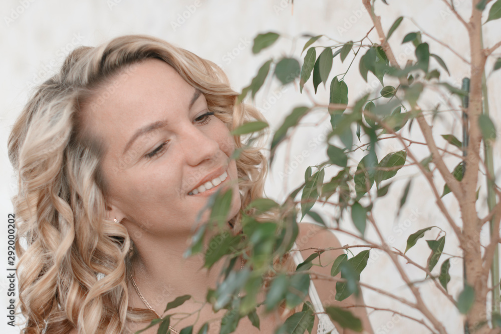 A young beautiful girl is watching and caring for a ficus plant in the morning. A young beautiful girl is watching and caring for a ficus plant in the morning.