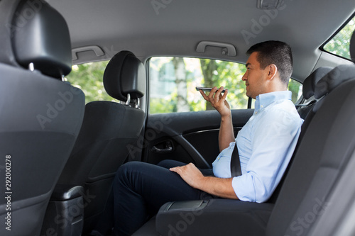 transport, business and technology concept - male passenger or businessman using voice command recorder on smartphone on back seat of taxi car © Syda Productions