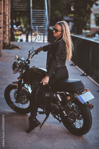 Portrait of beautiful woman in sunglasses and leather clothing on the motorbike.