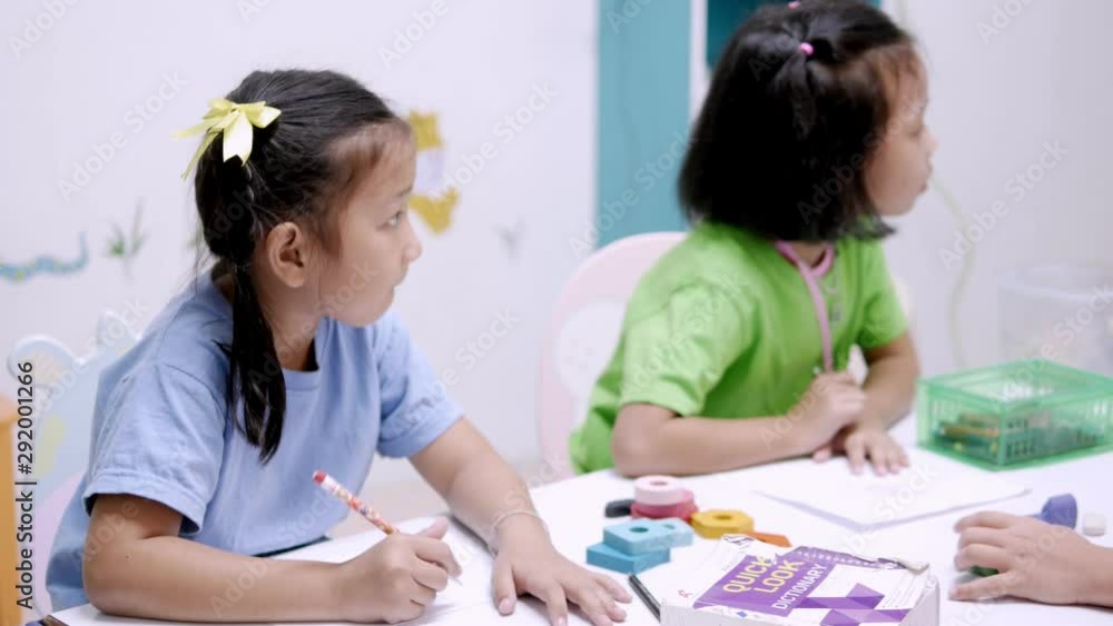 The Asian elementary school children are studying in the classroom with Asian female teacher. The Asian elementary school children are studying in the classroom with Asian female teacher.