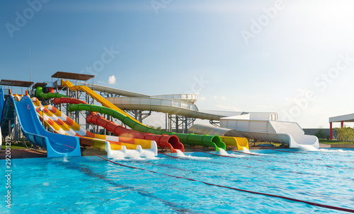 Water park, bright multi-colored slides with a pool. A water park without people on a summer day with a beautiful, cloudy blue sky