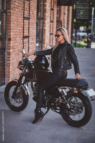 Sexy dramatic woman is parking her shiny new motorbike next to brick wall. © Fxquadro