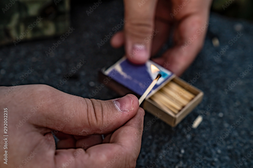 Obraz premium The man holds a burning match in his hand. In the other hand a box of matches