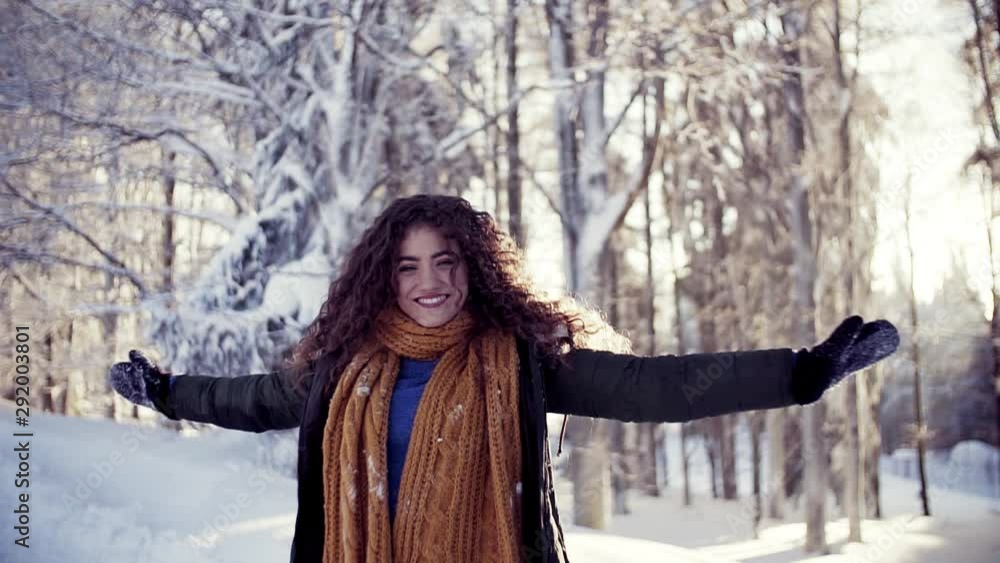 A front view portrait of young woman standing outdoors in snowy winter forest. A front view portrait of young woman standing outdoors in snowy winter forest.