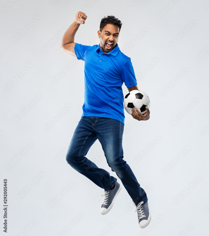 sport, leisure games and people concept - happy indian man or football fan with soccer ball jumping over grey background