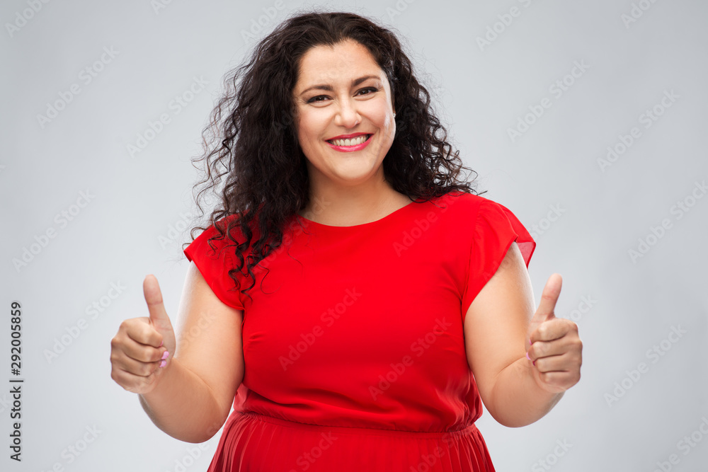 people and gesture concept - happy woman in red dress showing thumbs up over grey background people and gesture concept - happy woman in red dress showing thumbs up over grey background