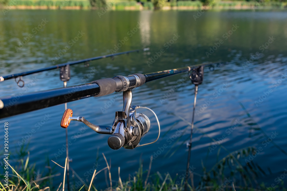 Closeup of a reel fishing rod on a prop and water background