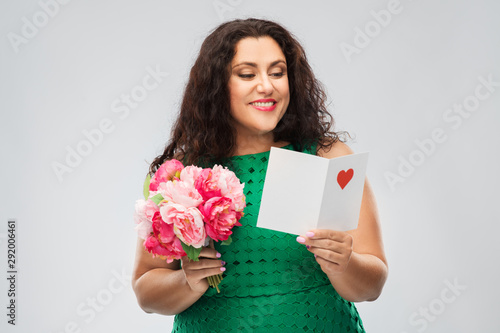 valentine's day, people and love concept - happy woman with flower bunch and greeting card over grey background