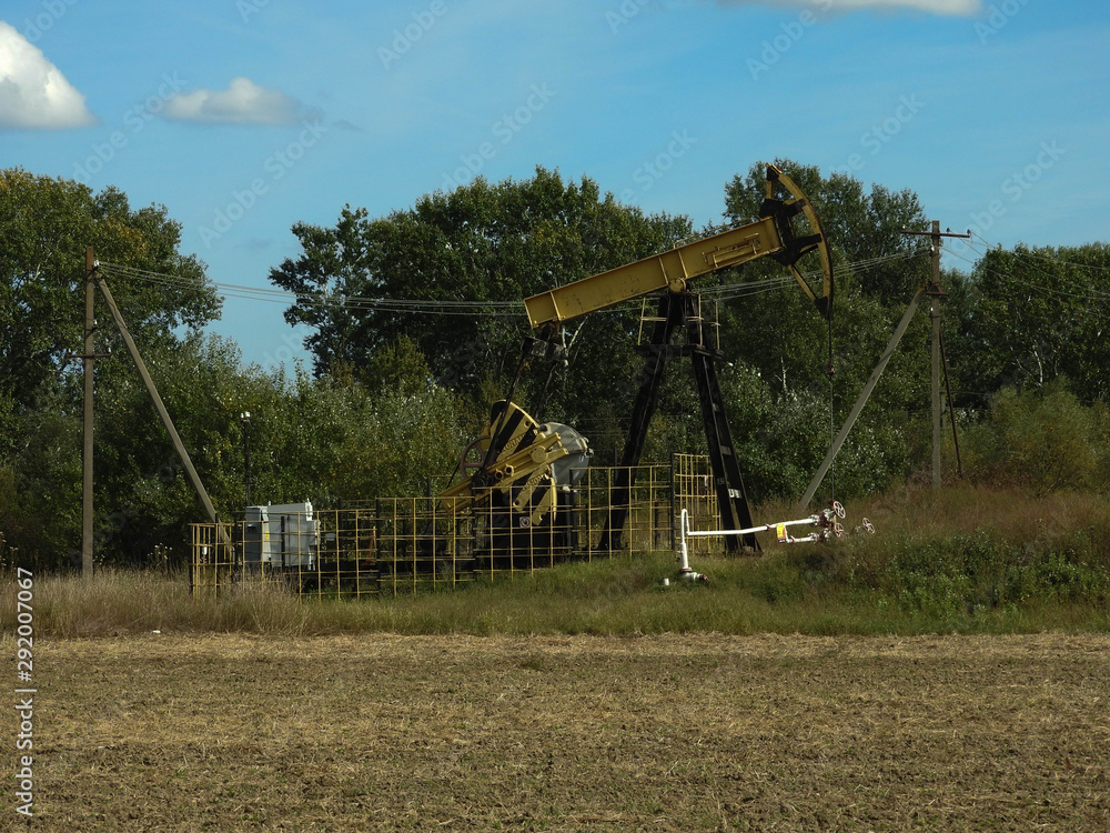 Oil pump wells for underground oil production works in the field on an autumn day Oil pump wells for underground oil production works in the field on an autumn day