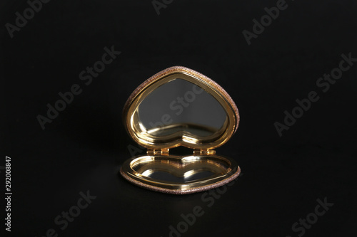 Heart shaped gold pocket mirror on black background