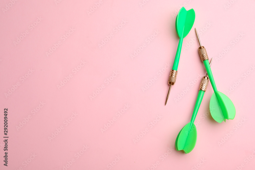 Green dart arrows on pink background, flat lay with space for text Green dart arrows on pink background, flat lay with space for text