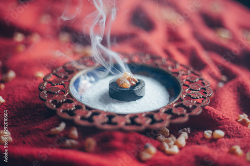 Frankincense burning on a hot coal. Frankincense is an aromatic resin, used for religious rites, incense and perfumes, incense smoke (color toned image) photo