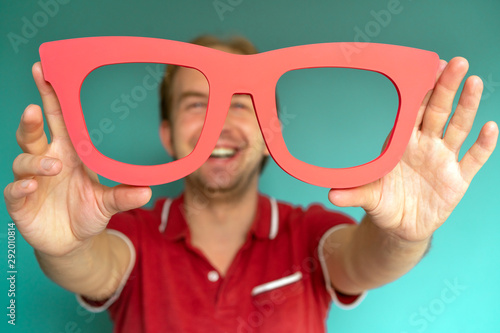 Photos Cheerful man in a red shirt holds big red glasses