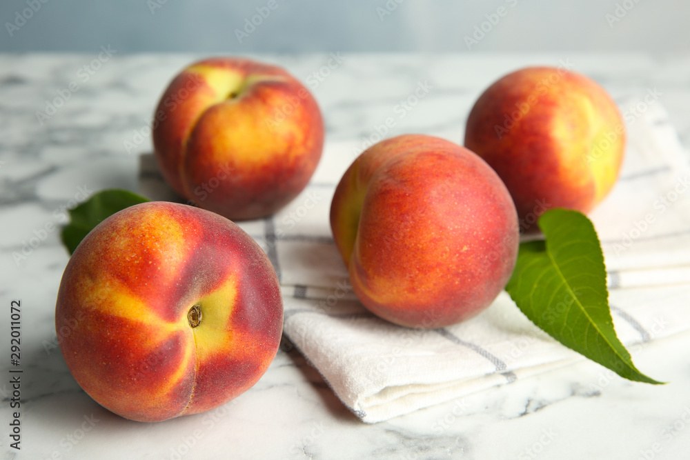 Fresh juicy peaches, leaves and fabric on marble table Fresh juicy peaches, leaves and fabric on marble table