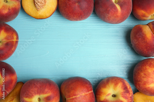 Frame made of fresh peaches on blue wooden table, top view with space for text