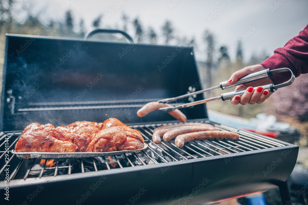 Hand of young woman grilling some meat and vegetable-meat skewers on huge  gas grill (color toned image) Stock Photo | Adobe Stock