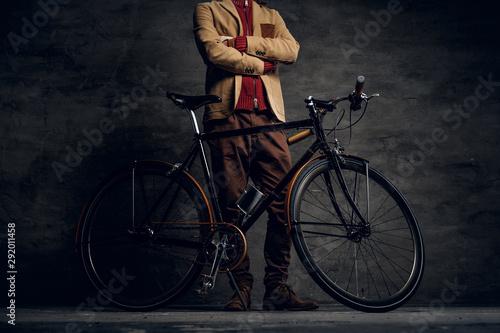 Man with his bicycle is posing for photographer at dark photo studio.