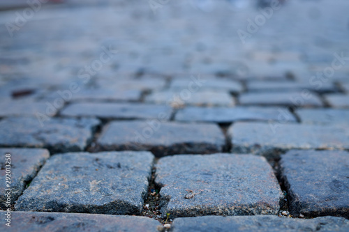 Stone pavement in perspective. Old street paved with stone blocks. Shallow depth of field. Vintage grunge texture.