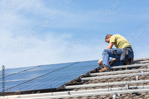 Installing solar photovoltaic panel system. Solar panel technician installing solar panels on roof. Alternative energy ecological concept.