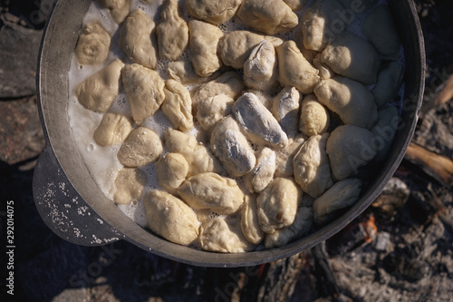 National Ukrainian food. Dumplings are boiling in a large cauldron at the stake.