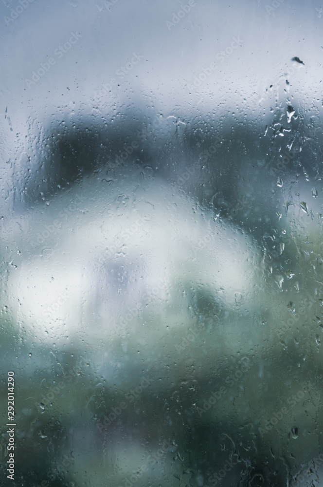 wet glass of window with raindrops, estate garden