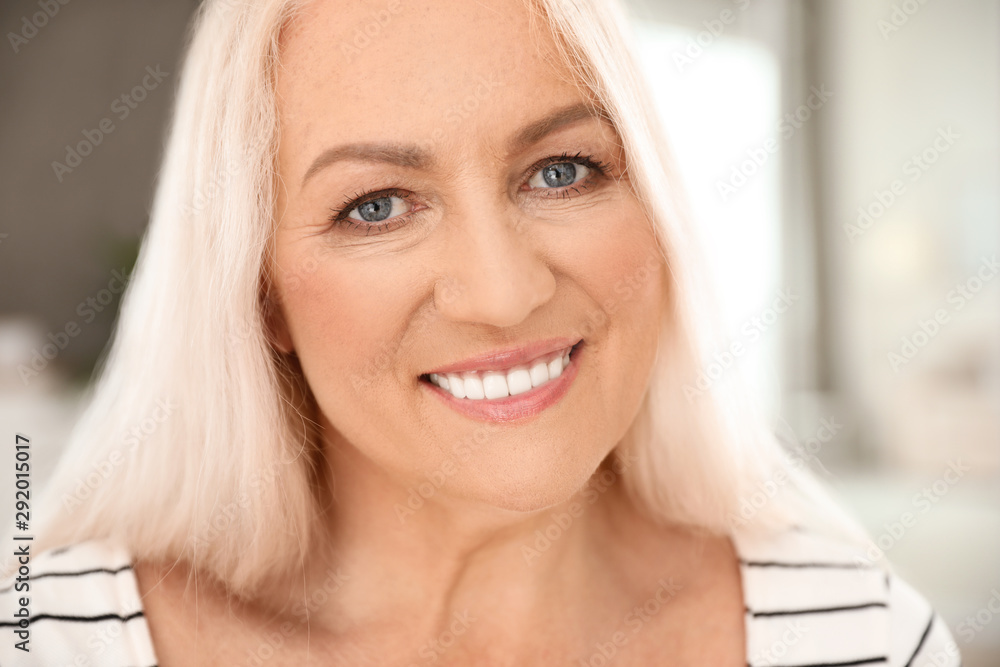 Portrait of mature woman with beautiful face on blurred background, closeup view - obrazy, fototapety, plakaty 
