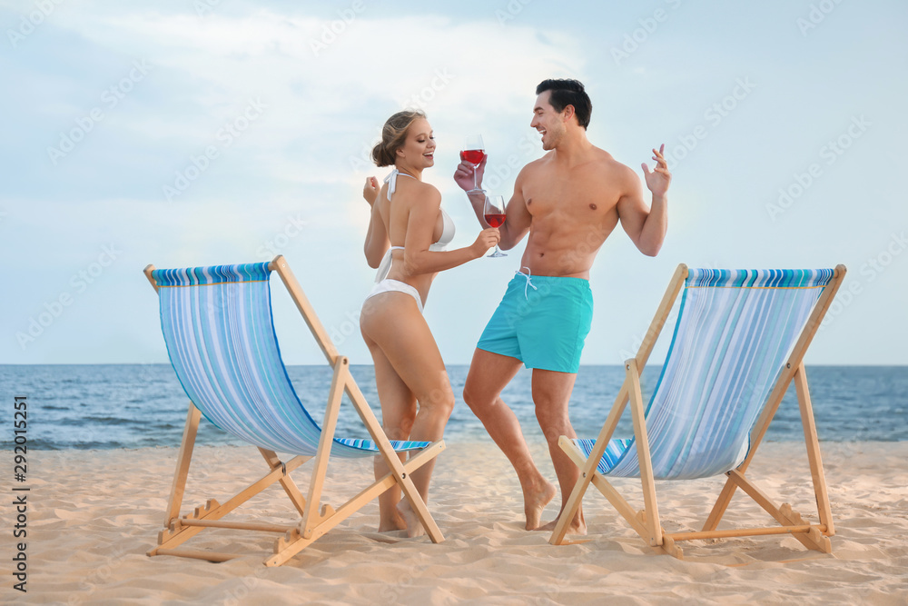 Happy young couple dancing near deck chairs at sea beach Happy young couple dancing near deck chairs at sea beach