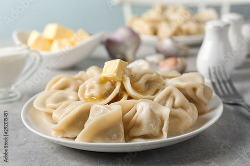 Tasty dumplings with butter on light grey table against blurred background